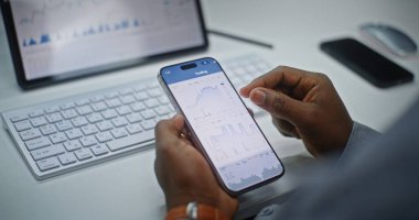 Finansal Analizci Smartphone ve Dijital Tablet Online Ticaret Uygulamasını Kullanarak Gerçek Zamanlı Borsa Çizelgelerini Kontrol Ediyor. Yatırım Bankası Ofisi 'nde çalışan Afro-Amerikan İşadamı. Kapat..