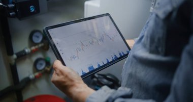 Dijital Tablet Bilgisayar kullanarak Gerçek zamanlı borsa tablolarını ve borsa çizelgelerini kontrol ediyorum. Atölyede Çalışma Saatlerinde Yatırım Yapan Adam, İş ve Çevrimiçi Ticareti Birleştiriyor. Görüntüyü Kapat.