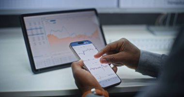 Smartphone ve Dijital Tablet Online Ticaret Uygulamasını kullanarak Afro-Amerikan Borsası Borsa Analizi ve Borsa Çizelgeleri. Ofiste çalışan Yatırım Ajanı. Kapat..