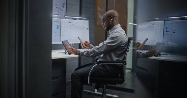 Çoklu Sayısal Aygıtlar ve Bilgisayarda Çoklu Monitör Masaüstü ile Afro-Amerikan Borsası borsası Gerçek-Zaman Hisselerini, Çizelgeleri İzliyor. Geceleri ofiste çalışan Profesyonel Yatırım Ajanı