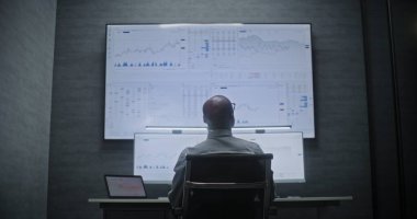 Multi-Monitor Workstation, Real-Time Stocks ve Exchange Market Charts ile bilgisayar üzerinde çalışan bir finans analisti. Afrikalı Amerikalı İşadamı Yatırım Bankası Ofisinde Gece Çalışıyor.