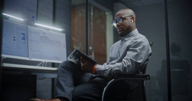 Gerçek zamanlı hisse senetlerini analiz eden finansal analist, Dijital Tablet ve Bilgisayar kullanan borsa grafikleri çoklu-monitör çalışma istasyonu. Afrikalı Amerikalı İşadamı Yatırım Bankası Ofisinde Çalışıyor.