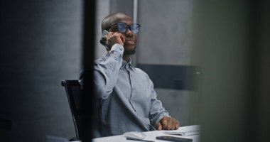 Afrikalı Amerikan Borsacı veya Finansal Analizci Bilgisayarı Kullanıyor ve İş Ortağına Cep Telefonu ile Konuşuyor. Finans Bürosu 'nda çalışan Profesyonel Yatırım Ajanı. Orta Çekim.