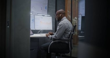 Telsiz Kulaklık Borsası İşlemcisi Gerçek Zamanlı Hisse Senedi İzleme, Çoklu İzleme Masası 'ndaki Borsa Çizelgeleri. Afrika-Amerika Yatırım Ajanı Geceleri Ofiste Çalışıyor.