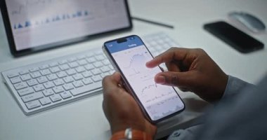 Finansal Analizci Smartphone ve Dijital Tablet Online Ticaret Uygulamasını Kullanarak Gerçek Zamanlı Borsa Çizelgelerini Kontrol Ediyor. Yatırım Bankası Ofisi 'nde çalışan Afro-Amerikan İşadamı. Kapat..