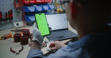 Man Checking Real-time Stocks, Exchange Market Charts dizüstü bilgisayarda ve Smartphone ile Green Screen Mock Up atölyesinde. Uygulama veya İş Reklamcılığı için Yer Tutucu ile Görüntü Şablonu. Kapat..