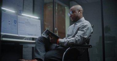 Gerçek zamanlı hisse senetlerini analiz eden finansal analist, Dijital Tablet ve Bilgisayar kullanan borsa grafikleri çoklu-monitör çalışma istasyonu. Afrikalı Amerikalı İşadamı Yatırım Bankası Ofisinde Çalışıyor.