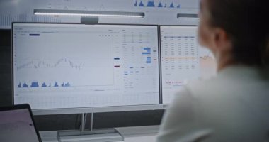 Multi-Monitor Workstation, Real-Time Stocks ve Exchange Market Charts ile bilgisayar üzerinde çalışan kadın finans analisti. Başarılı İşkadını Yatırım Bankası Ofisinde Gece Çalışıyor.