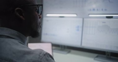 Multi-Monitor Workstation ile bilgisayar üzerinde çalışan Finansal Analizci, Gerçek zamanlı Borsa Çizelgelerini İzleyen, Telefonda Konuşan. Afrikalı Amerikalı İşadamı Ofiste Çalışıyor. Kapat..