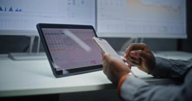 Çevrimiçi Ticaret Uygulaması Kullanılarak Finansal Analizci Gerçek Zamanlı Borsa Çizelgelerini, Akıllı Telefon ve Dijital Ekranları Kontrol Ediyor. Afrikalı Amerikalı İşadamı Yatırım Bankası Ofisi 'nde çalışıyor. Kapat..