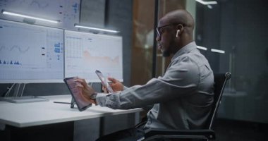 Afro-Amerikan Finansal Analizci, Gerçek-Zaman Hisselerini Analiz Etme, Dijital Tablet, Akıllı Telefon ve Bilgisayar Piyasa Grafikleri ve Çoklu-Monitör Çalışma İstasyonu. Yatırım Bankası Ofisinde İşadamı.