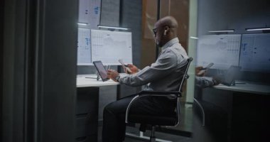 Çoklu Sayısal Aygıtlar ve Bilgisayarda Çoklu Monitör Masaüstü ile Afro-Amerikan Borsası borsası Gerçek-Zaman Hisselerini, Çizelgeleri İzliyor. Geceleri ofiste çalışan Profesyonel Yatırım Ajanı