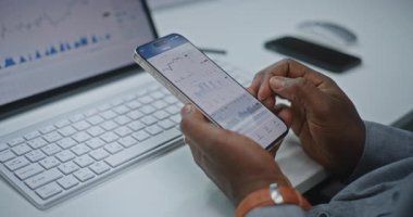 Afro-Amerikan Finansal Analizci Smartphone ve Dijital Tablet 'in Online Ticari Uygulamasını Kullanarak Gerçek Zamanlı Borsa Çizelgelerini Kontrol Ediyor. Yatırım Bankası Ofisi 'nde çalışan bir işadamı. Kapat..