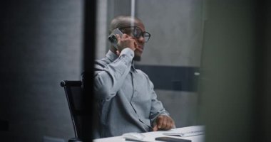 Afrikalı Amerikan Borsacı veya Finansal Analizci Bilgisayarı Kullanıyor ve İş Ortağına Cep Telefonu ile Konuşuyor. Finans Bürosu 'nda çalışan Profesyonel Yatırım Ajanı. Orta Çekim.