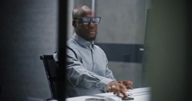 Afrikalı Amerikalı Profesyonel Finans Analisti ya da Borsa Simsarı Klavyede Yazıyor, Bilgisayar Kullanıyor. Gece Yatırım Bankası Ofisi veya Finans Ajansı 'nda başarılı bir İşadamı.