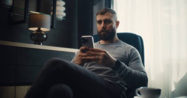 Finansal Analist Smartphone üzerinde çalışıyor, Gerçek zamanlı borsa ve borsa grafiklerini analiz ediyor, yatırım yapıyor. Başarılı İşadamı, Konforlu Yatırım Bankası Ofisinde Çalışıyor. Doli Vuruşu.