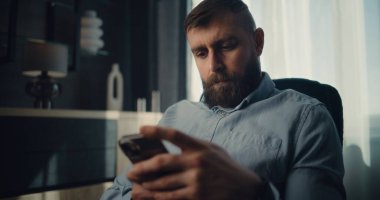 Akıllı Telefon Kullanarak Konsantre Profesyonel Borsa Komisyoncusu Gerçek zamanlı Borsa ve Borsa Çizelgelerini İzliyor. Finans Dairesi 'nin rahat ofisinde çalışan başarılı Yatırım Ajanı.