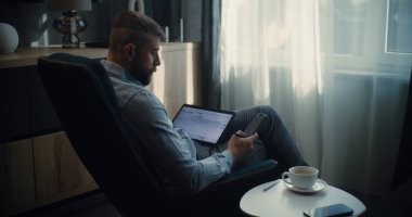 Tablet Bilgisayar ve Smartphone kullanan Profesyonel Borsa İşlemcisi, Çevrimiçi Ticaret Uygulamasında Gerçek Zamanlı Borsa ve Borsa Çizelgelerini İzliyor. Ofiste çalışan Yatırım Ajanı. Sabit Çekim.