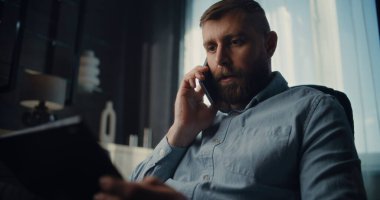 Profesyonel Borsa Tüccarı Cep Telefonu Konuşuyor, Gerçek zamanlı borsa ve tablet bilgisayar kullanarak borsa grafiklerini izliyor. Finans Dairesi 'nin rahat ofisinde çalışan Yatırım Ajanı.