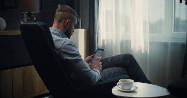 Smartphone üzerinde çalışan Profesyonel Finans Uzmanı, Çevrimiçi Ticaret Uygulamasında Gerçek Zamanlı Borsa ve Borsa Çizelgelerini İzliyor. Konforlu Yatırım Bankası Ofisinde Başarılı İşadamı.