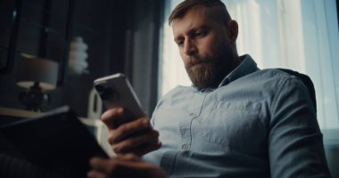 Profesyonel Borsa Tüccarı Cep Telefonu Konuşuyor, Gerçek zamanlı borsa ve tablet bilgisayar kullanarak borsa grafiklerini izliyor. Finans Dairesi 'nin rahat ofisinde çalışan Yatırım Ajanı.