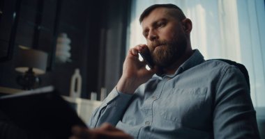 Profesyonel Borsa Tüccarı Cep Telefonu Konuşuyor, Gerçek zamanlı borsa ve tablet bilgisayar kullanarak borsa grafiklerini izliyor. Finans Dairesi 'nin rahat ofisinde çalışan Yatırım Ajanı.