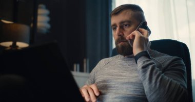 Profesyonel Finans Uzmanı Laptop üzerinde çalışıyor, Gerçek zamanlı hisse senetleri ve borsa grafiklerini izliyor, telefon görüşmesi yapıyor. Başarılı İşadamı Konforlu Yatırım Bankası Ofisinde Çalışıyor.