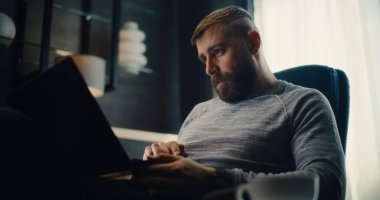 Profesyonel Borsa Komisyoncusu Telefonla Konuşuyor, Gerçek zamanlı borsa grafiklerini analiz ediyor ve dizüstü bilgisayar kullanıyor. Başarılı Yatırım Ajanı Finans Dairesi 'nin rahat ofisinde çalışıyor..