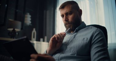 Dijital Stylus ile Tablet Bilgisayar üzerinde çalışan düşünceli Finansal Analizci, Gerçek zamanlı Borsa Tablolarını İzliyor. Başarılı İşadamı Konforlu Yatırım Bankası Ofisinde Çalışıyor.