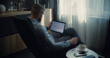 Çevrimiçi Ticaret Uygulamasında Tablet Bilgisayar üzerinde çalışan Finansal Analizci, Gerçek zamanlı Borsa Çizelgeleri İzleniyor. Başarılı İşadamı Konforlu Yatırım Bankası Ofisinde Çalışıyor.