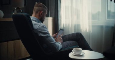 Smartphone üzerinde çalışan Profesyonel Finans Uzmanı, Çevrimiçi Ticaret Uygulamasında Gerçek Zamanlı Borsa ve Borsa Çizelgelerini İzliyor. Konforlu Yatırım Bankası Ofisinde Başarılı İşadamı.