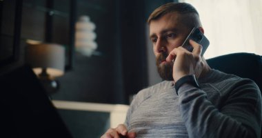 Profesyonel Mali Analistin Telefonu Var, Dizüstü bilgisayarda çalışıyor, Gerçek zamanlı borsa ve borsa grafiklerini izliyor. Başarılı İşadamı Konforlu Yatırım Bankası Ofisinde Çalışıyor.