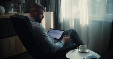 Tablet Bilgisayar ve Smartphone kullanan Profesyonel Borsa İşlemcisi, Çevrimiçi Ticaret Uygulamasında Gerçek Zamanlı Borsa ve Borsa Çizelgelerini İzliyor. Ofiste çalışan Yatırım Ajanı. Sabit Çekim.