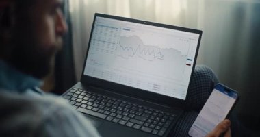 Smartphone ve Laptop üzerinde çalışan Profesyonel Finans Uzmanının Kapanışı, Gerçek Zamandaki Hisselerin İzlenmesi, Çevrimiçi Ticaret Uygulamasında Değişim Piyasası Grafikleri. İçişleri Bakanlığı 'nda başarılı bir iş adamı..
