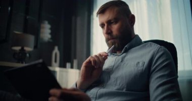 Dijital Stylus ile Tablet Bilgisayar üzerinde çalışan düşünceli Finansal Analizci, Gerçek zamanlı Borsa Tablolarını İzliyor. Başarılı İşadamı Konforlu Yatırım Bankası Ofisinde Çalışıyor.