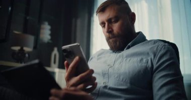 Profesyonel Borsa Tüccarı Cep Telefonu Konuşuyor, Gerçek zamanlı borsa ve tablet bilgisayar kullanarak borsa grafiklerini izliyor. Finans Dairesi 'nin rahat ofisinde çalışan Yatırım Ajanı.