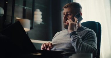 Profesyonel Borsa Komisyoncusu Telefonla Konuşuyor, Gerçek zamanlı borsa grafiklerini analiz ediyor ve dizüstü bilgisayar kullanıyor. Başarılı Yatırım Ajanı Finans Dairesi 'nin rahat ofisinde çalışıyor..