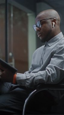 Gerçek zamanlı hisse senetlerini analiz eden finansal analist, Dijital Tablet ve Bilgisayar kullanan borsa grafikleri çoklu-monitör çalışma istasyonu. Afrikalı Amerikalı İşadamı Bankada çalışıyor. Dikey Çekim.