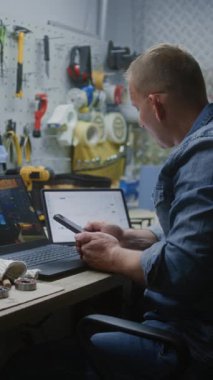 Bilgisayarda Online Ticaret Dersi İzleyen Çalışan, Gerçek zamanlı borsa grafiklerini kontrol eden, akıllı telefon kullanan, dijital tablet kullanan. Mesai saatleri içinde İnsan Uzaktan Öğrenme Ticaret. Dikey Çekim.