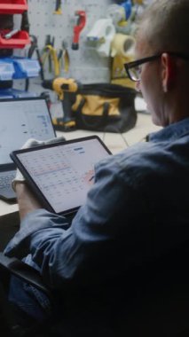 Dijital Tablet ve Laptop kullanarak Gerçek zamanlı borsa tablolarını ve borsa çizelgelerini kontrol ediyorum. Atölyede Çalışma Saatlerinde Yatırım Yapan Adam, İş ve Çevrimiçi Ticareti Birleştiriyor. Dikey Çekim