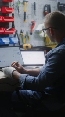 El işi yapan zanaatkar, gerçek zamanlı hisse senedi, dizüstü bilgisayarda ve tablet bilgisayarda piyasa grafikleri izliyor. İş günü atölyede yatırım yapan, ticaretle işi birleştiren adam. Dikey Çekim.