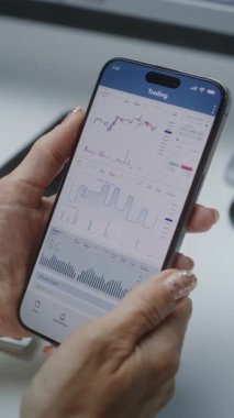 Smartphone Online Ticaret Mobil Uygulamasını kullanarak Gerçek zamanlı borsa grafiklerini kontrol eden kadın finans analisti. Yatırım Bankası 'nda çalışan bir iş kadını. Yakın çekim. Dikey Çekim.
