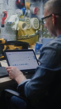 Sanatçı, Online Trading Webinar 'ı Dizüstü bilgisayarda izliyor, Gerçek zamanlı hisse senetleri ve piyasa grafiklerini dijital tablet kullanarak izliyor. Atölyede İnsan Uzaktan Öğrenme Ticaret Günü. Dikey Çekim.