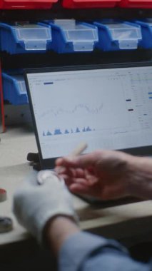 El işi yapan tamirci, gerçek zamanlı hisse senedi kontrolü, dizüstü bilgisayar ve dijital tabletteki borsa grafikleri. İş saatlerinde yatırım yapan adam, ticaret ile işi birleştiren adam. Dikey Çekim.