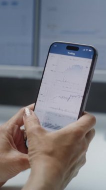 Dişi Borsa Komisyoncusu Gerçek Zamanlı Borsa İzleme, Smartphone 'da Borsa Listeleri ve Çevrimiçi Ticaret Uygulamasını kullanarak Dijital Ekranlar. Ofiste çalışan Yatırım Ajanı. Dikey Görüntüyü Kapat