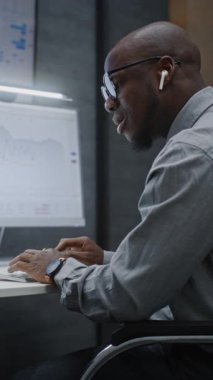 Gerçek zamanlı hisse senedi ve borsa grafiklerini bilgisayarda Multi-Monitor Workstation, Talking, having Call ile birlikte takip eden finansal analist. Afrikalı Amerikalı İşadamı Ofiste Çalışıyor. Dikey Çekim.