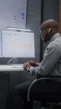 Telsiz Kulaklık Borsası İşlemcisi Gerçek Zamanlı Hisse Senedi İzleme, Çoklu İzleme Masası 'ndaki Borsa Çizelgeleri. Afro-Amerikan Yatırım Ajanı çalışıyor. Dikey Çekim.