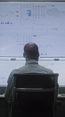 Menkul Kıymetler Borsası Gerçek Zamanlı Borsa İzleme, Çoklu Monitör Masaüstü Ayarları ile Bilgisayarda Borsa Tabloları Değiştirme, Telefonda Konuşma. Ofisteki Afro-Amerikan Yatırım Ajanı. Dikey Çekim.