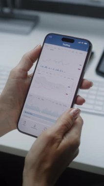 Smartphone ve Dijital Tablet Online Ticaret Uygulamasını kullanarak borsa grafikleri ve borsa grafiklerini gerçek zamanlı olarak izleyen kadın borsa simsarı. Ofiste çalışan Yatırım Ajanı. Yakın çekim. Dikey Çekim.