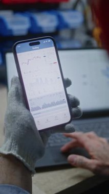 Adam akıllı telefon ve dizüstü bilgisayarda Gerçek zamanlı borsa grafiklerini kontrol ediyor. Çalışanların çalışma saatleri sırasında kripto para yatırımı yapması, Ticaret ile işi birleştirmesi. Yakın çekim. Dikey Çekim.